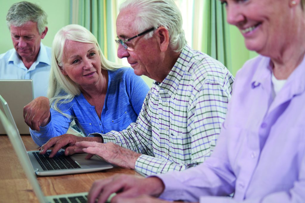 Teacher With Senior Students In Computing Adult Education Class