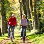 Senior,Man,And,Woman,Exercising,With,Bicycles,Outdoors,,They,Are