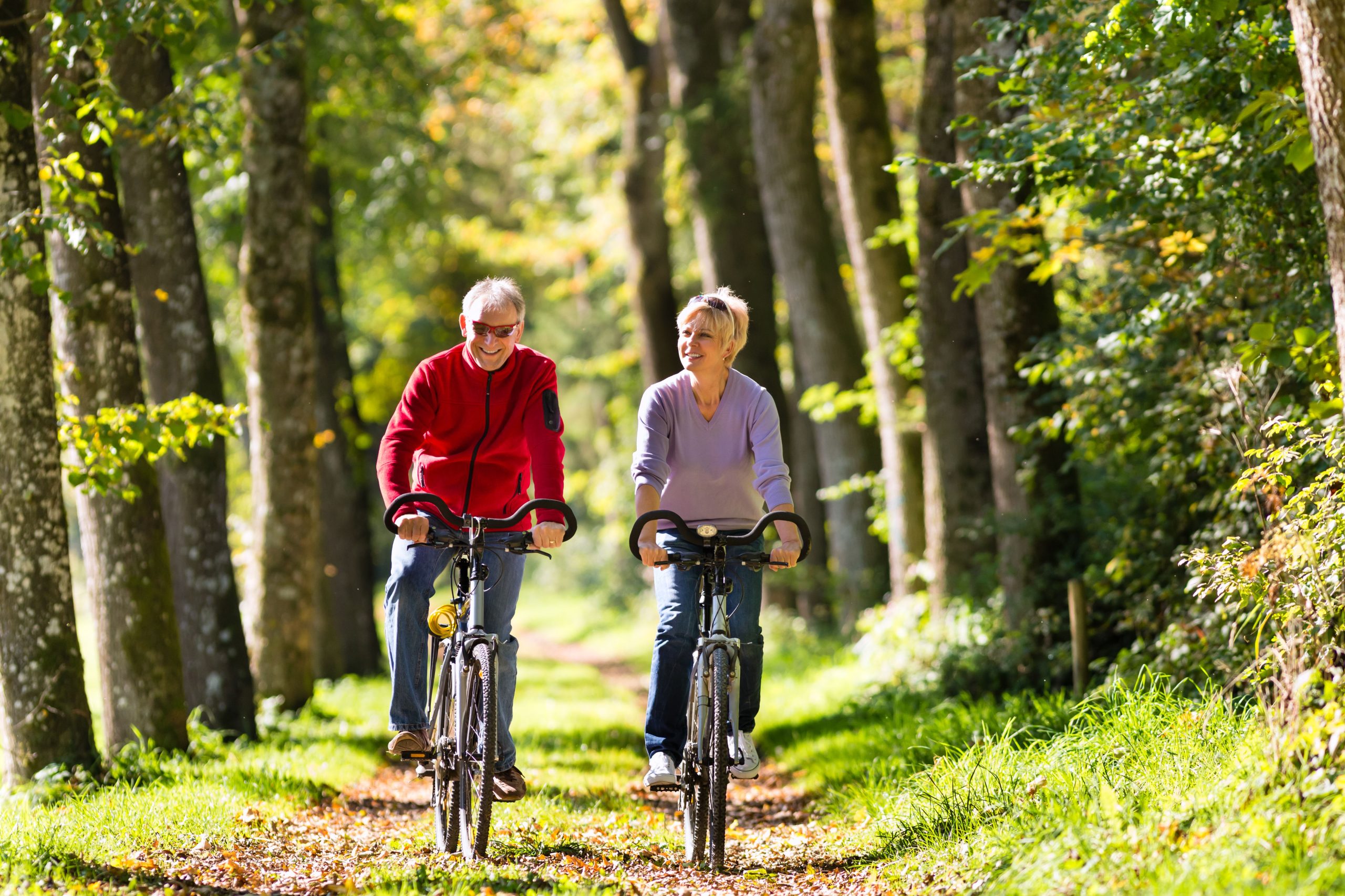Senior,Man,And,Woman,Exercising,With,Bicycles,Outdoors,,They,Are
